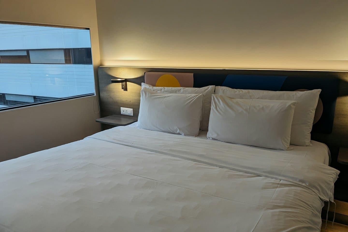 Un letto d'albergo con lenzuola bianche e una testiera in legno.